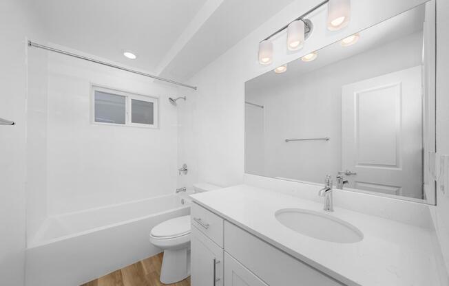 A white bathroom with a toilet, sink, and mirror.