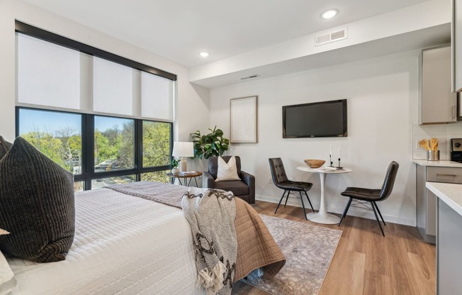 A modern bedroom with a large bed and a flat screen TV mounted on the wall.