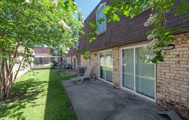 A patio with a table and chairs is surrounded by a brick wall and trees.