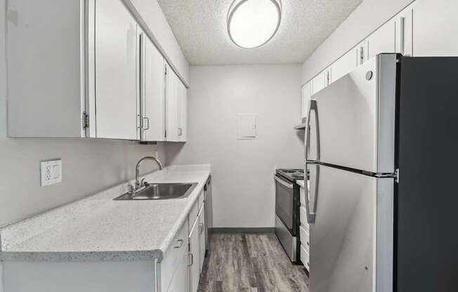 A kitchen with a black refrigerator and white cabinets.