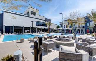 a pool with lounge chairs and a fire pit and tanning beds and cabana 