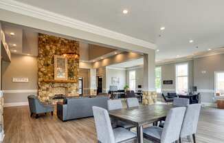 the gathering room has a large stone fireplace and a table with chairs