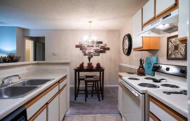 a kitchen with white appliances and a dining room with a table at The Summit Apartments, Memphis, Tennessee