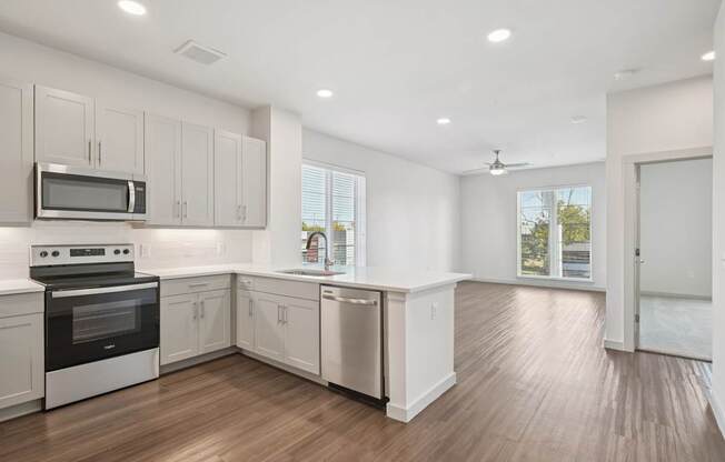 A kitchen with white cabinets and a wooden floor.