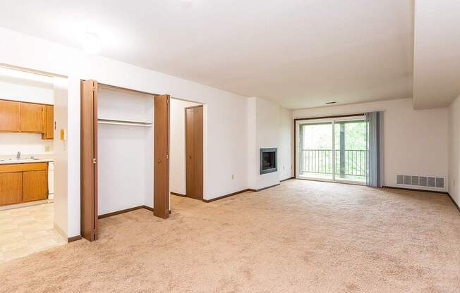 A large, empty room with a sliding glass door leading to a balcony.