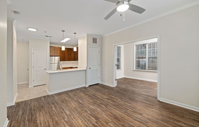 an empty living room and kitchen with a ceiling fan