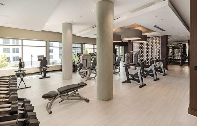 a gym with weights and chairs and a large window