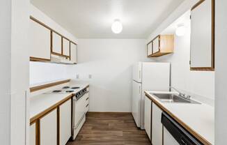 an empty kitchen with white appliances and wood flooring