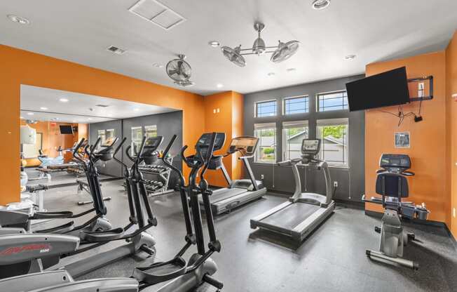 a gym with cardio equipment and a flat screen tv