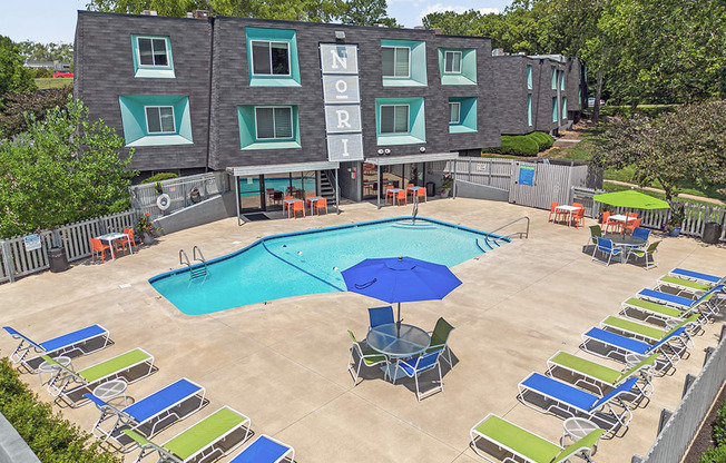 an aerial view of a swimming pool and patio with chairs and an umbrella