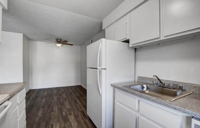 A kitchen with a white refrigerator and a sink.