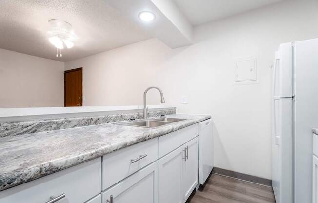 A kitchen with a marble countertop and white cabinets. at Bristol Ridge, Urbandale, IA