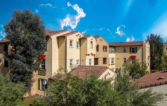 a view of a group of apartment buildings with trees in front of them