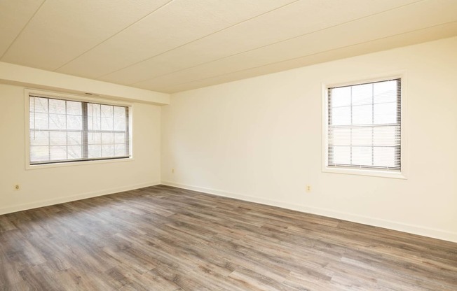 a bedroom with hardwood floors and two windows