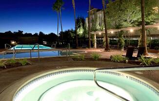 a pool at night with a hotel in the background
