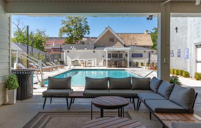 a swimming pool is seen from a patio with couches and tables