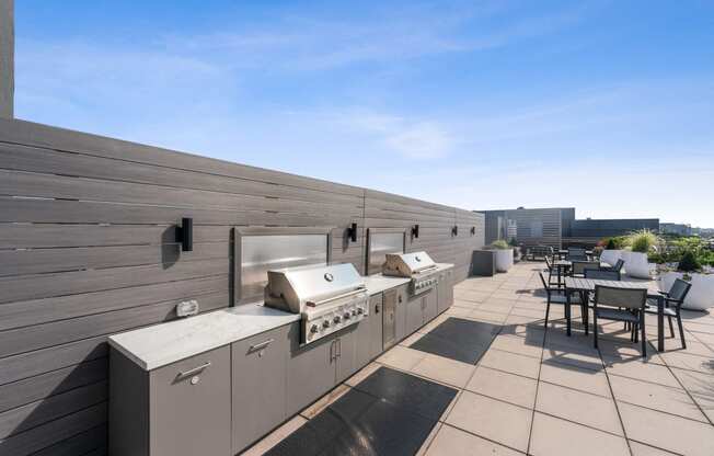 the outdoor patio has barbecue grills and a dining area with tables and chairs