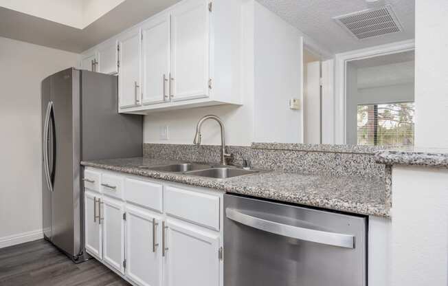 a kitchen with white cabinets and a stainless steel refrigerator