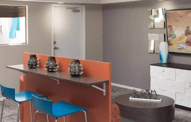 A modern kitchen with orange bar stools and a grey countertop.