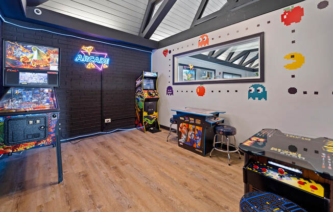 A room with a wooden floor and a wall with a neon sign that says "ARCADE".