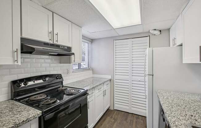A kitchen with a black stove top oven and white cabinets.