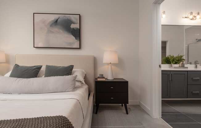 a bedroom with a bed and a night stand and a bathroom
