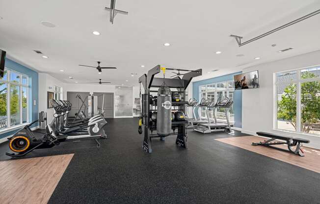 a gym with treadmills and other exercise equipment in a room with windows