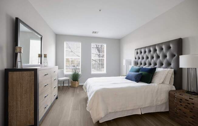 A bedroom with a large bed, a wooden dresser, and a mirror.