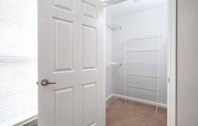a walk in closet with a white door and a closet with white racks