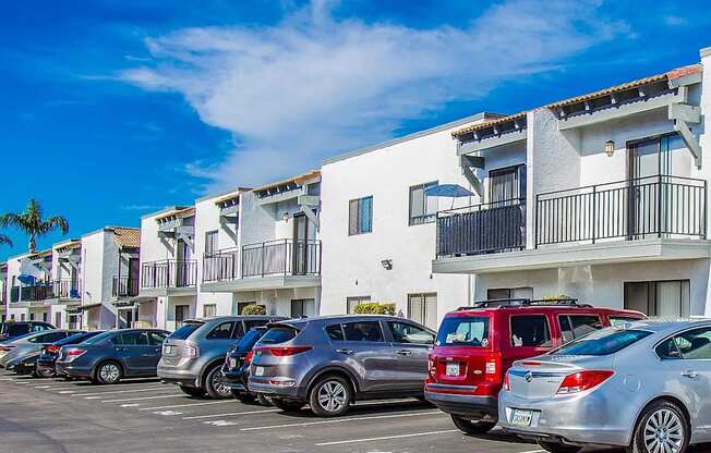 a parking lot with cars parked in front of apartments