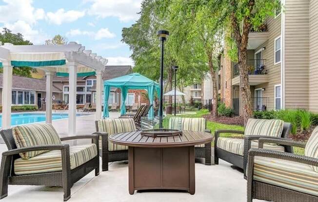 a patio with a table and chairs and a pool in the background