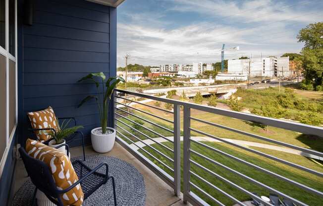 a balcony with a chair and a potted plant and a view of the city  at Abberly Noda Vista Apartment Homes, Charlotte, NC