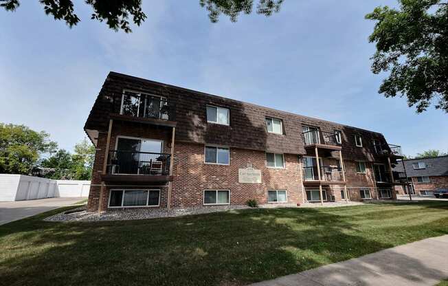 a brick apartment building with a lawn and a blue sky