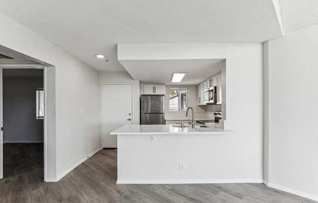 an open kitchen and living room with white walls and wood flooring