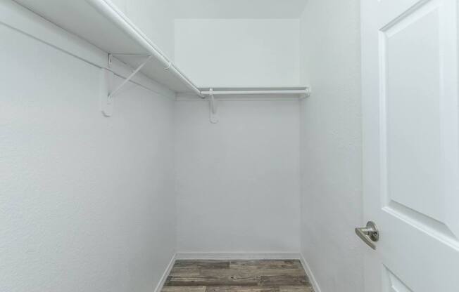 A white door is on the right side of a room with a white wall and a white ceiling.