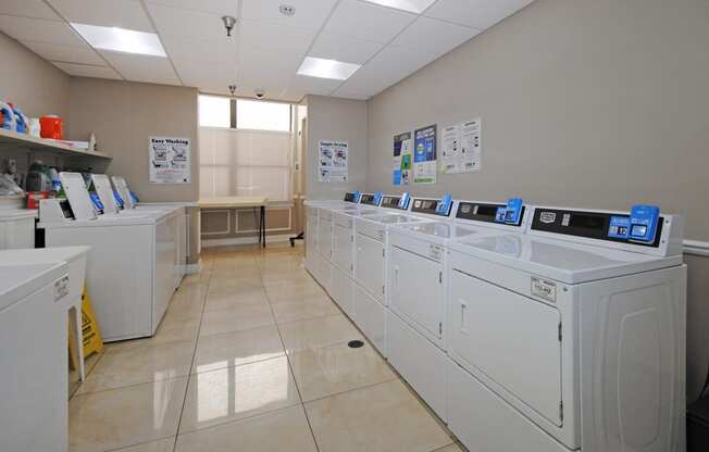 a row of washing machines in a laundry room with washers and dryers