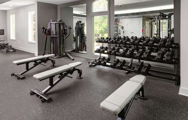 a gym with weights and benches in the center of the room