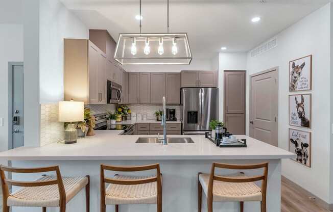a kitchen with a large island with three chairsat Weylyn Luxury Apartments, Laveen, AZ 85339