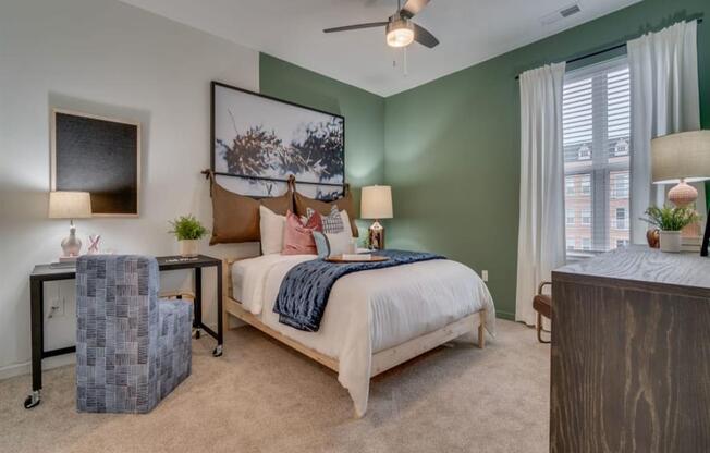 a bedroom with a bed and a chair in front of a window at Flats at West Broad Village, Glen Allen, 23060