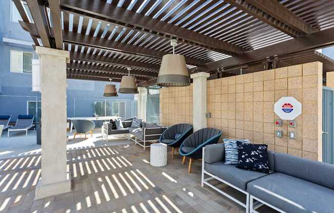 A patio with a couch, chairs, and a wall with a circular sign on it.