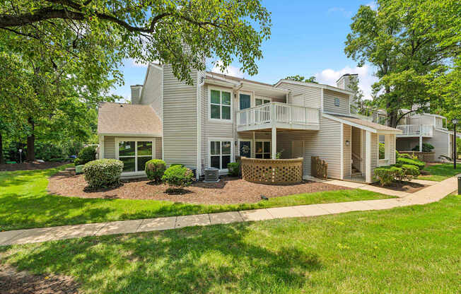 A large house with a well-manicured lawn and trees in the background.