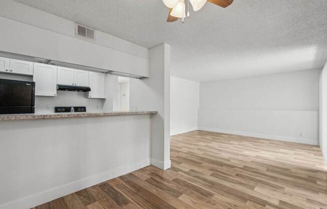 A kitchen with white cabinets and a black fridge.