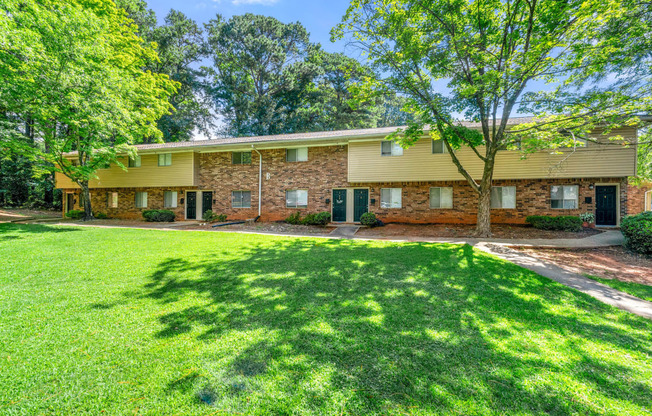 the front of a house with a lawn and trees