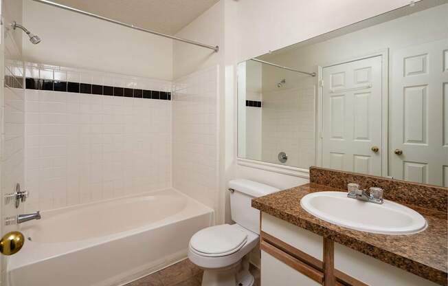 A white bathroom with a brown granite counter top.
