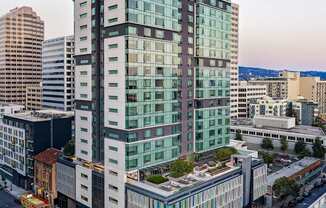 A modern glass building is situated on a busy street.