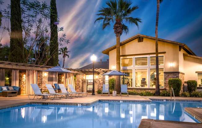 A house with a pool in front of it at night.