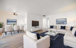 A modern living room with white furniture and a flat screen TV.