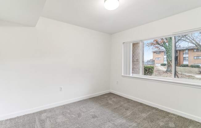 an empty living room with a large window and carpet