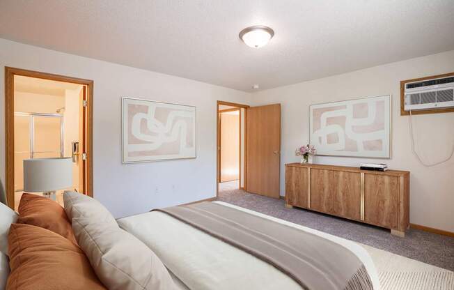 A bedroom with a large bed and two framed artworks on the wall.