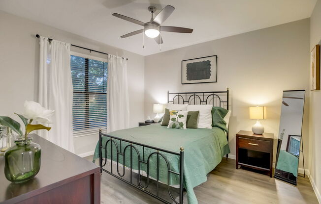 A bedroom with a bed, nightstand, and a ceiling fan.